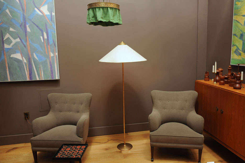 A floor lamp made of brass with a cane wrapped rod, shade covered in fabric.